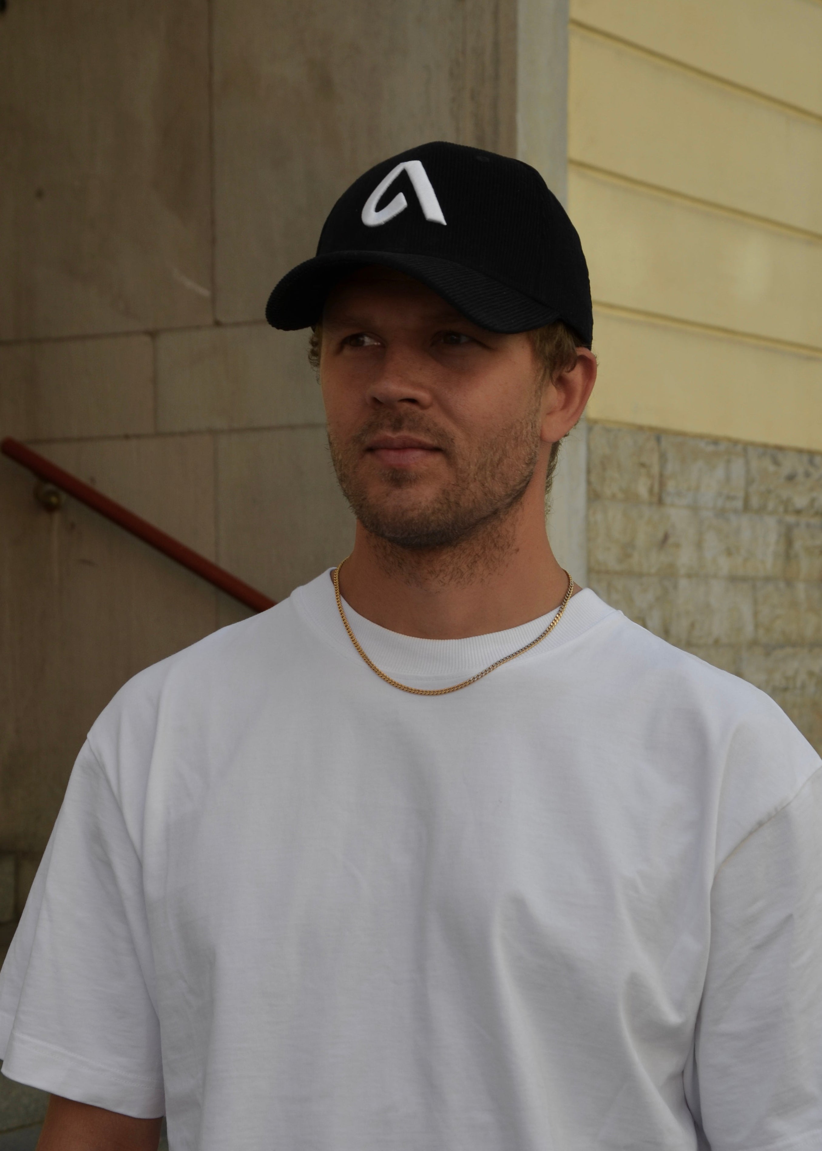 Black corduroy unisex cap with embroidery, structured front and adjustable metal buckle strap